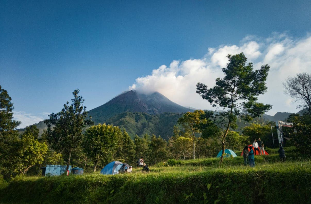 Pemandangan gunung dengan tenda berkemah di padang rumput
