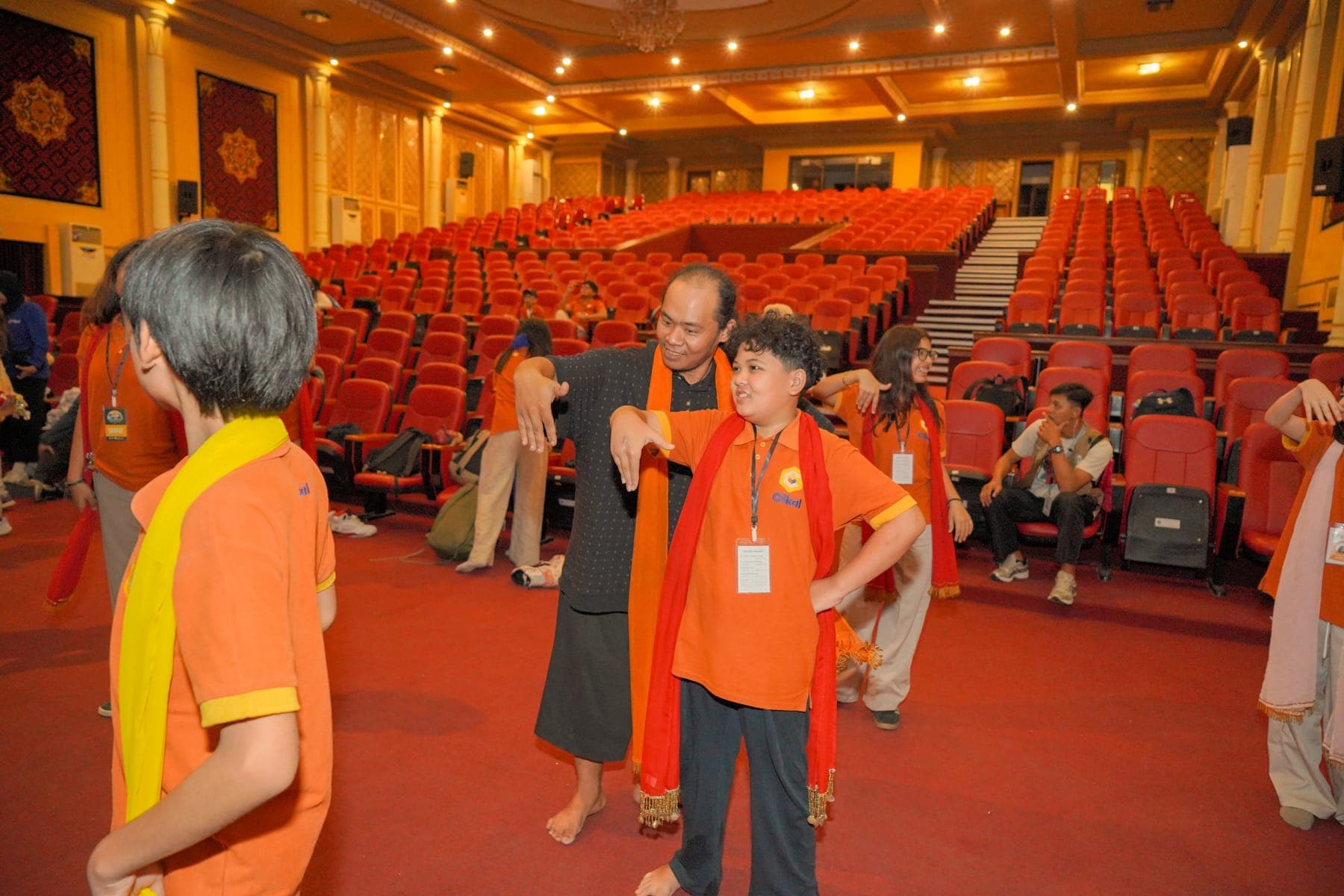 Peserta mengenakan selendang oranye di dalam auditorium