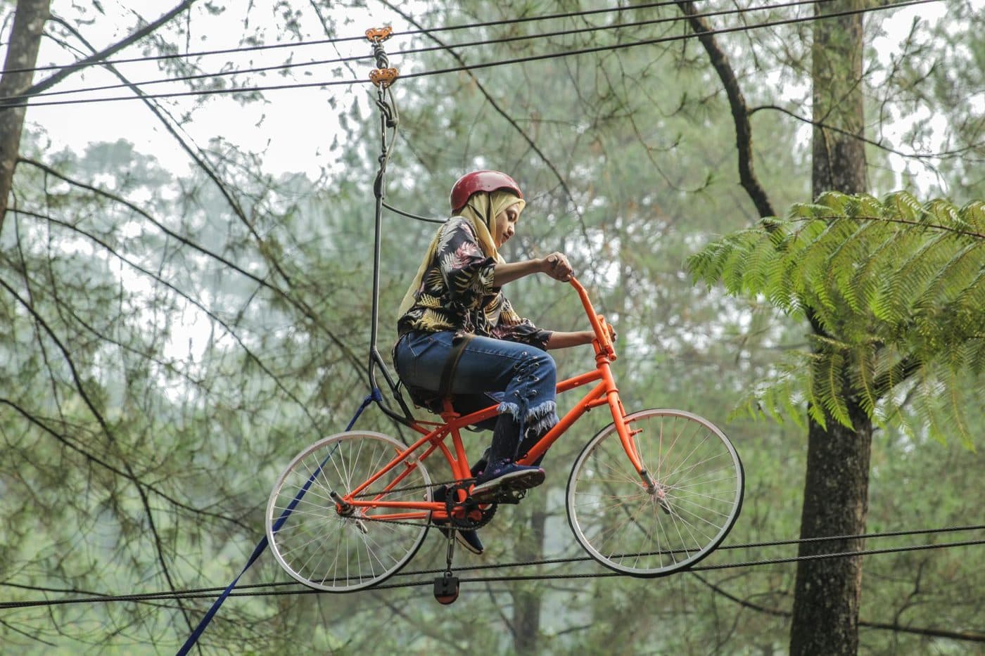 Peserta menaiki sepeda di atas tali flying fox di dalam hutan