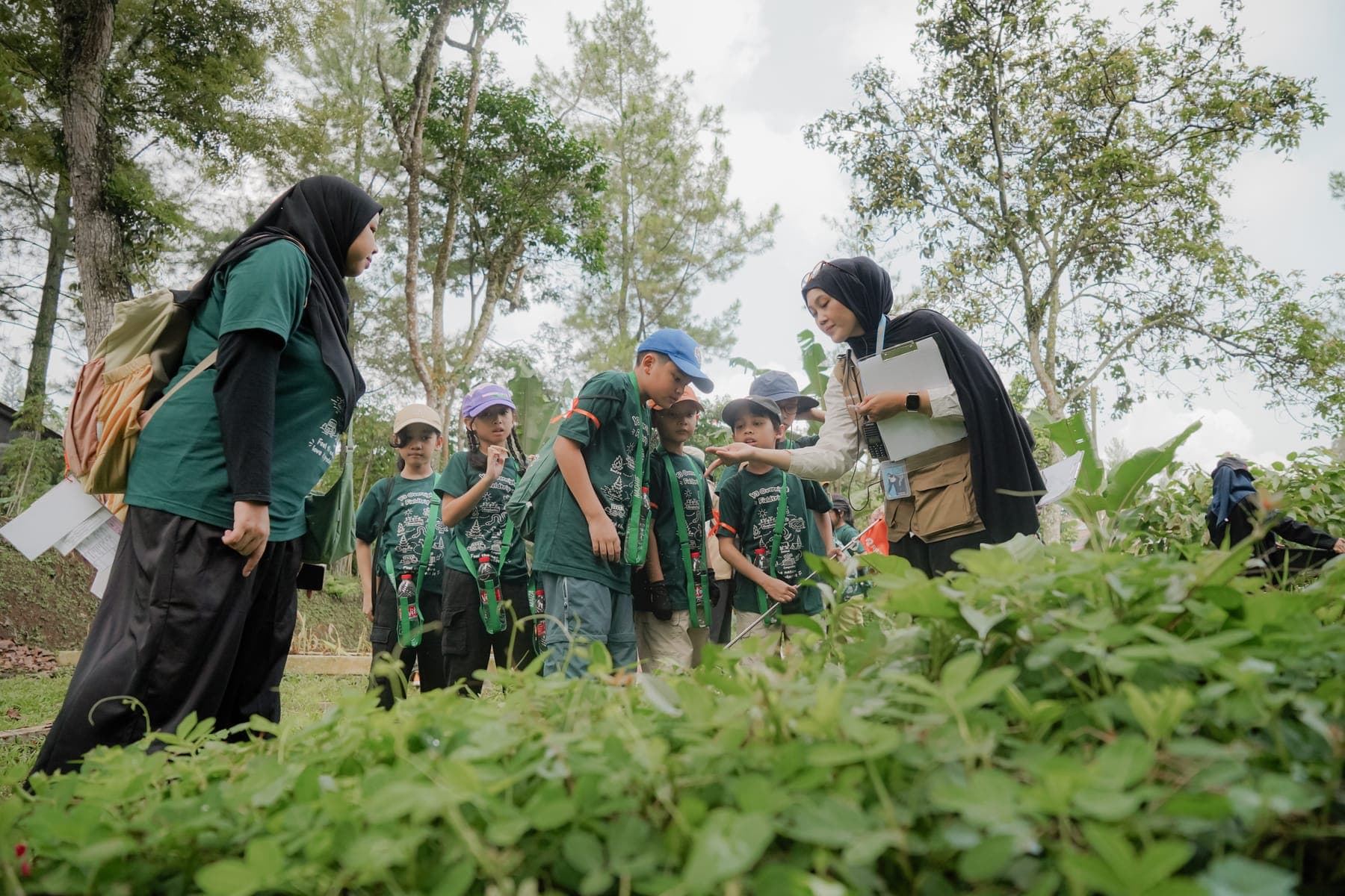 Siswa berdiri di lahan berlumpur sambil menanam bibit mangrove dengan celana digulung