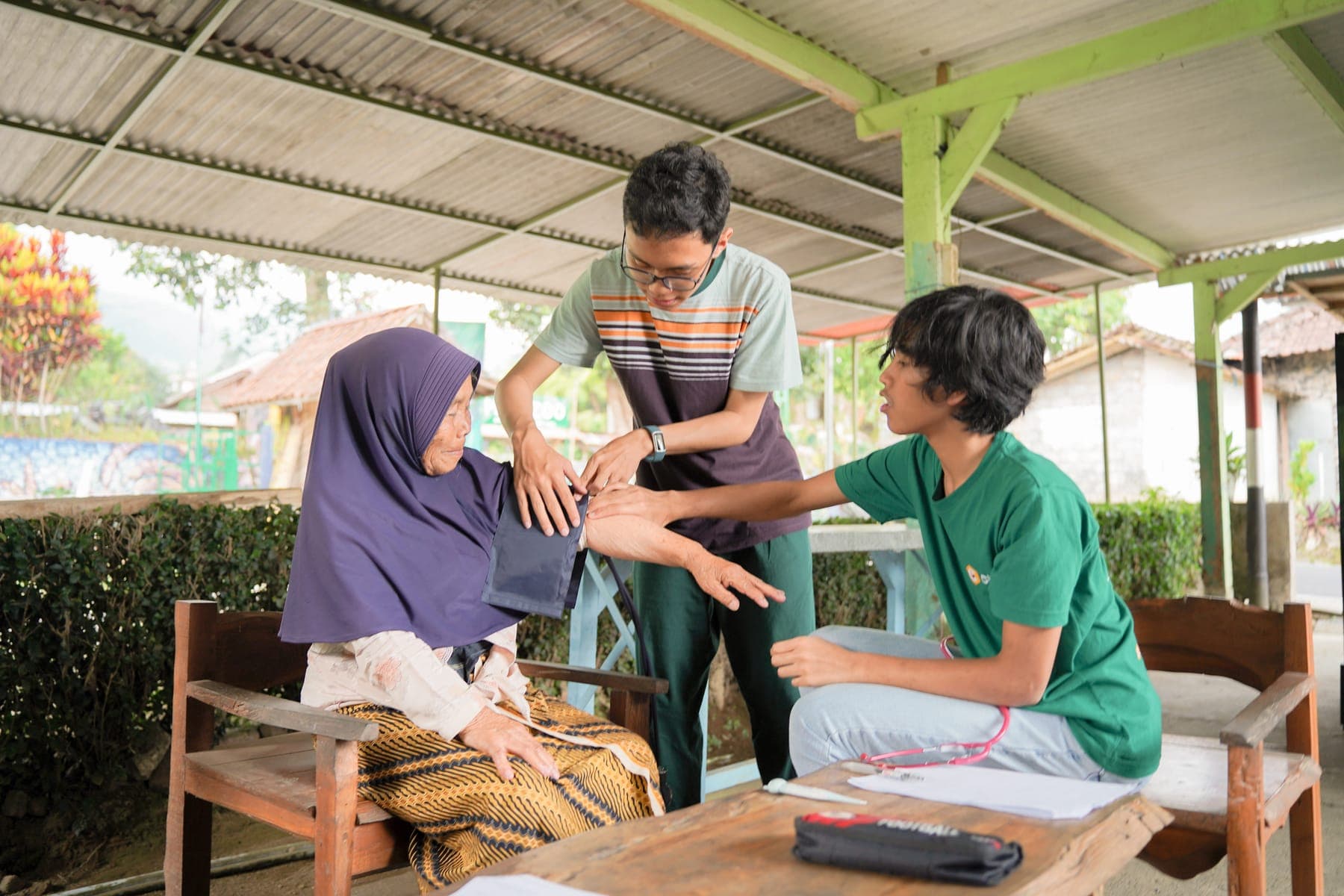 Dua siswa membantu tuan rumah mengangkat hasil kebun di halaman belakang rumah kayu
