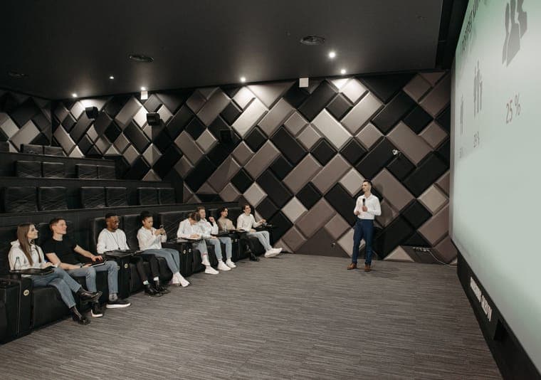 Pembicara memaparkan materi di depan layar proyektor pada sebuah konferensi di auditorium