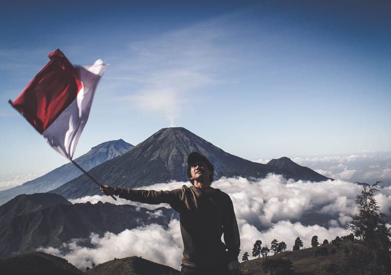 Pendaki mengibarkan bendera Merah Putih di puncak gunung di atas lautan awan